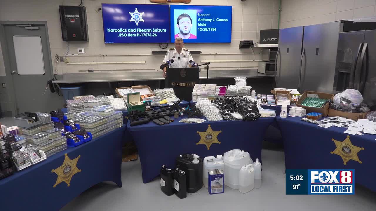 Sheriff Joe Lopinto at the Jefferson Parish Sheriff's Office briefing on Aug. 26, 2026, with seized product laid out on tables: vials, pills, raw chemical containers and firearms